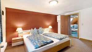 A bedroom with two beds, nightstands, and a ceiling light. - Apartment 'Hecke' with Shared Garden and Wi-Fi (Weddingstedt)