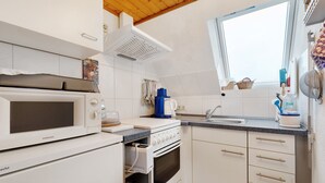 A compact kitchen with a microwave, oven, and sink. - Apartment 'Hecke' with Shared Garden and Wi-Fi (Weddingstedt)