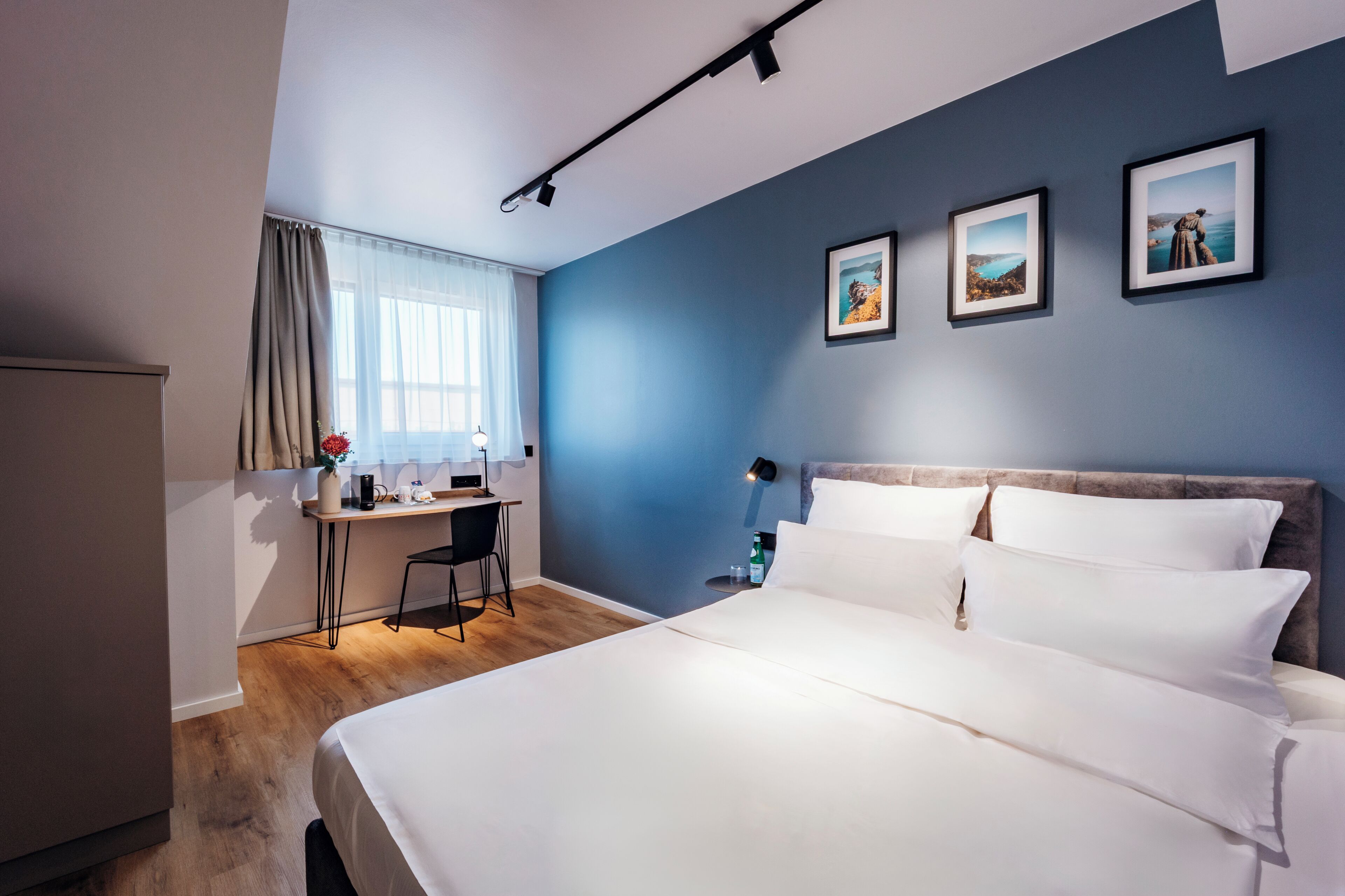 A hotel room with a bed, a desk, and a chair.