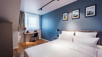 A hotel room with a bed, a desk, and a chair.