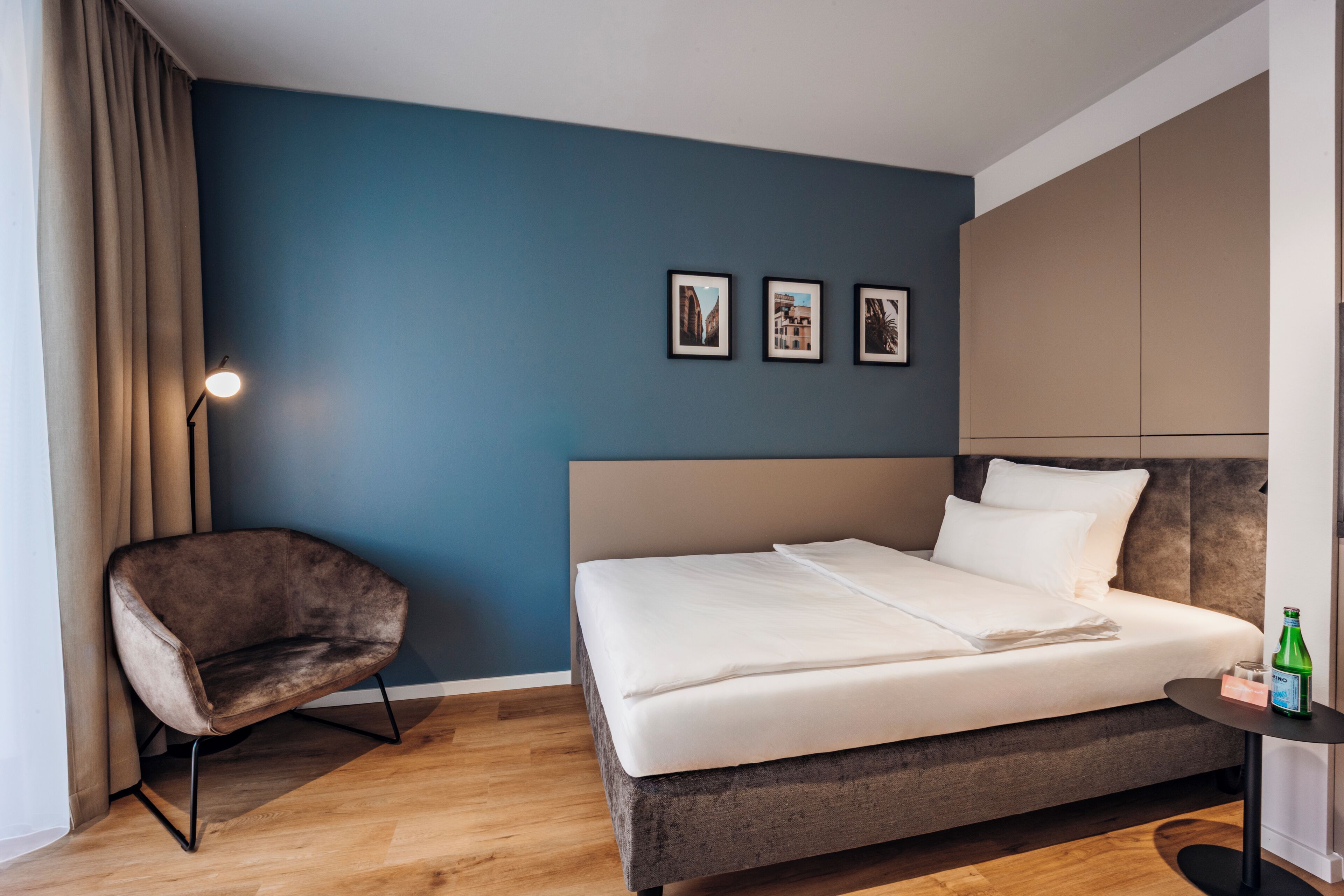 Ein Schlafzimmer mit Bett, Stuhl, Nachttisch und Lampe.