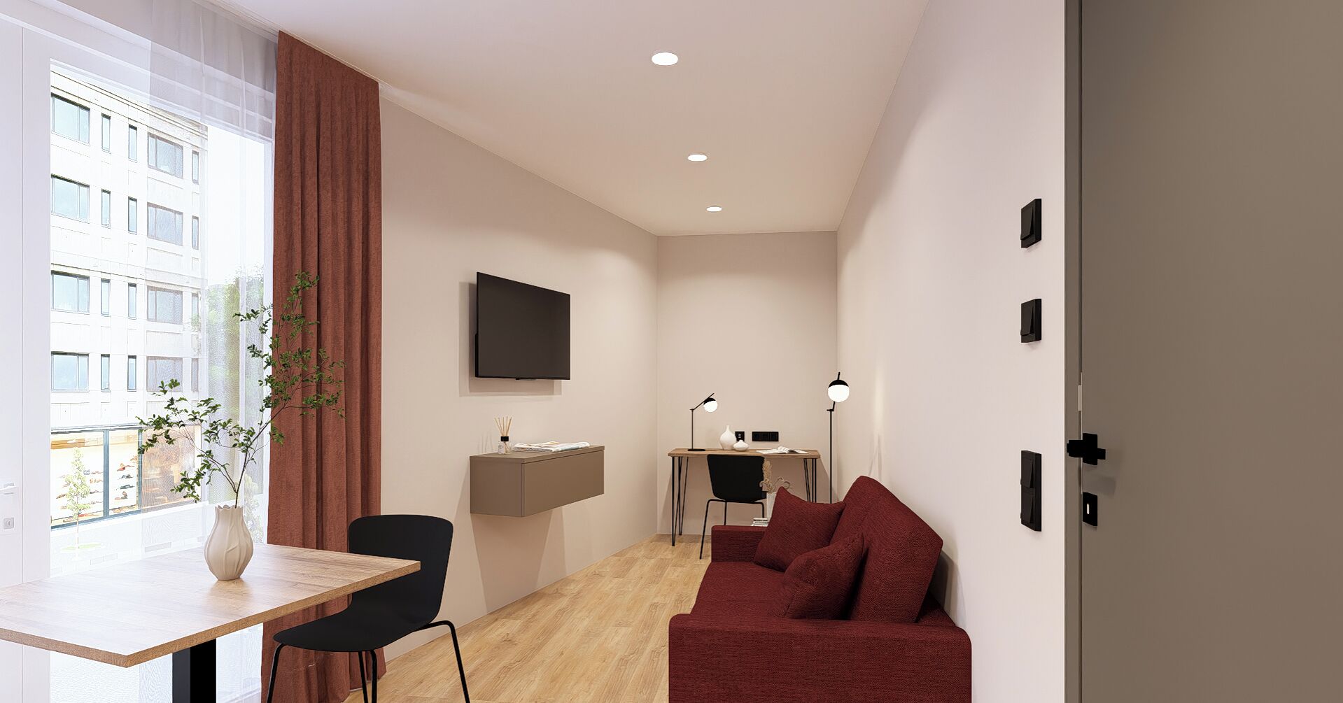 Une pièce moderne et bien éclairée, avec un bureau en bois, un canapé rouge, un téléviseur fixé au mur et une grande fenêtre donnant sur des immeubles.