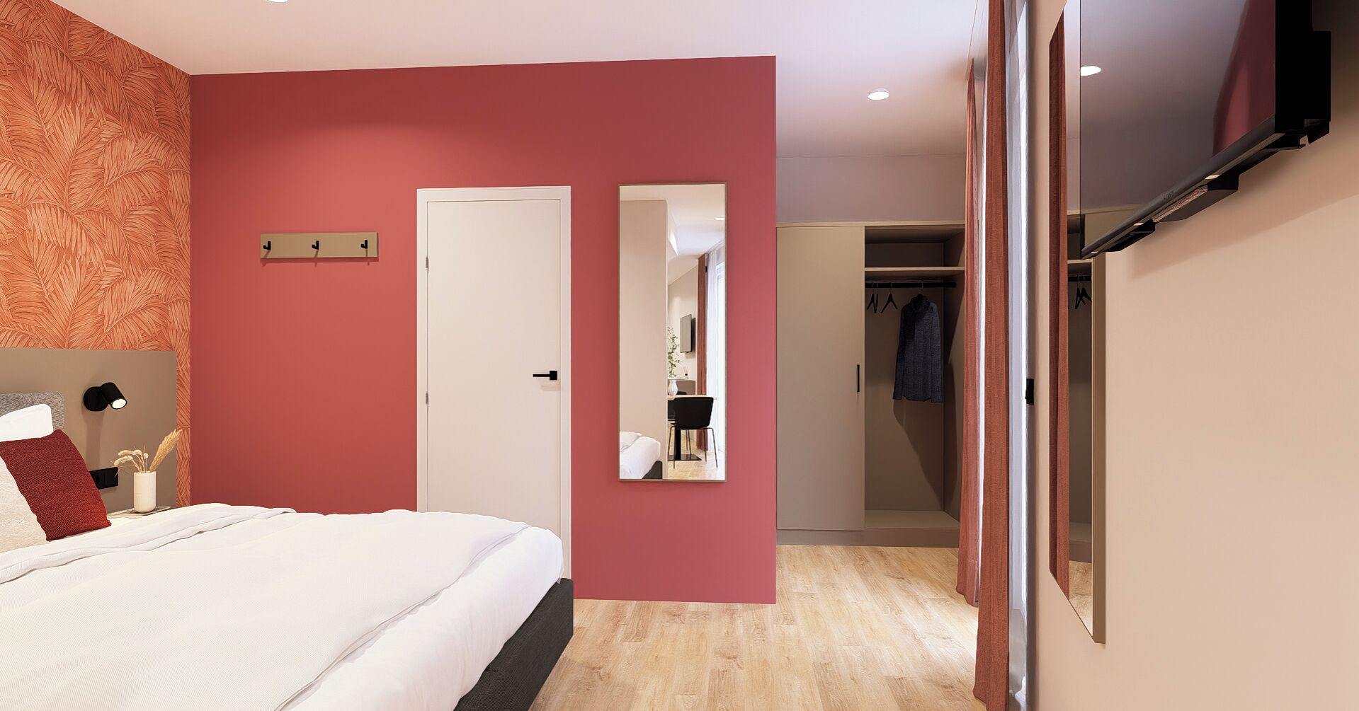 A hotel room with a bed, a wardrobe, a mirror, and a desk with a chair.