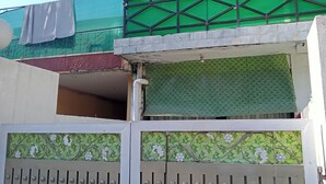 A gated entrance with a metal gate and a green mesh fence above. - Sameer Guest House (Islamabad)