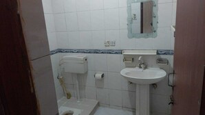 A small bathroom with a toilet, sink, and mirror. - Sameer Guest House (Islamabad)