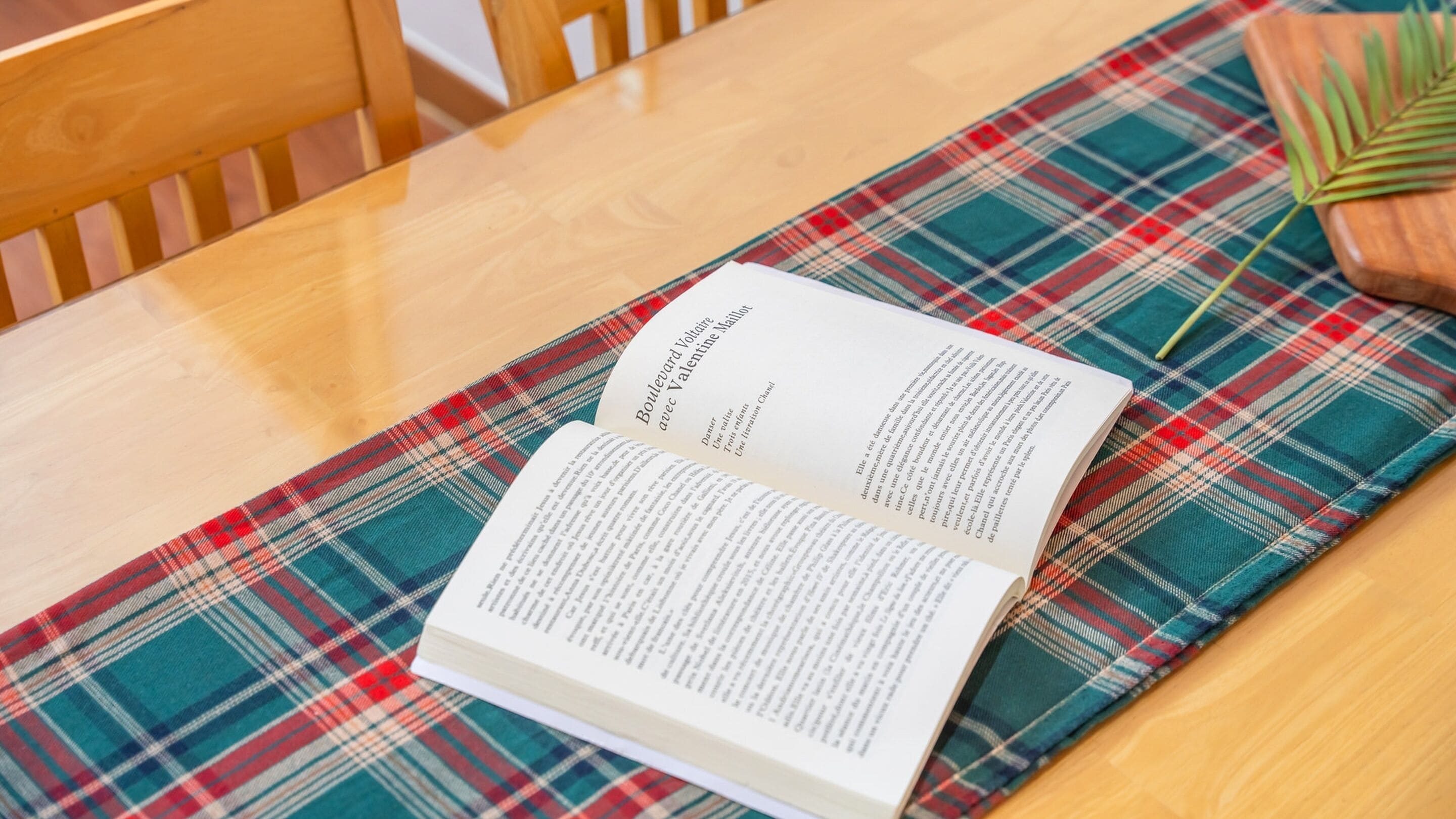 An open book on a plaid tablecloth.