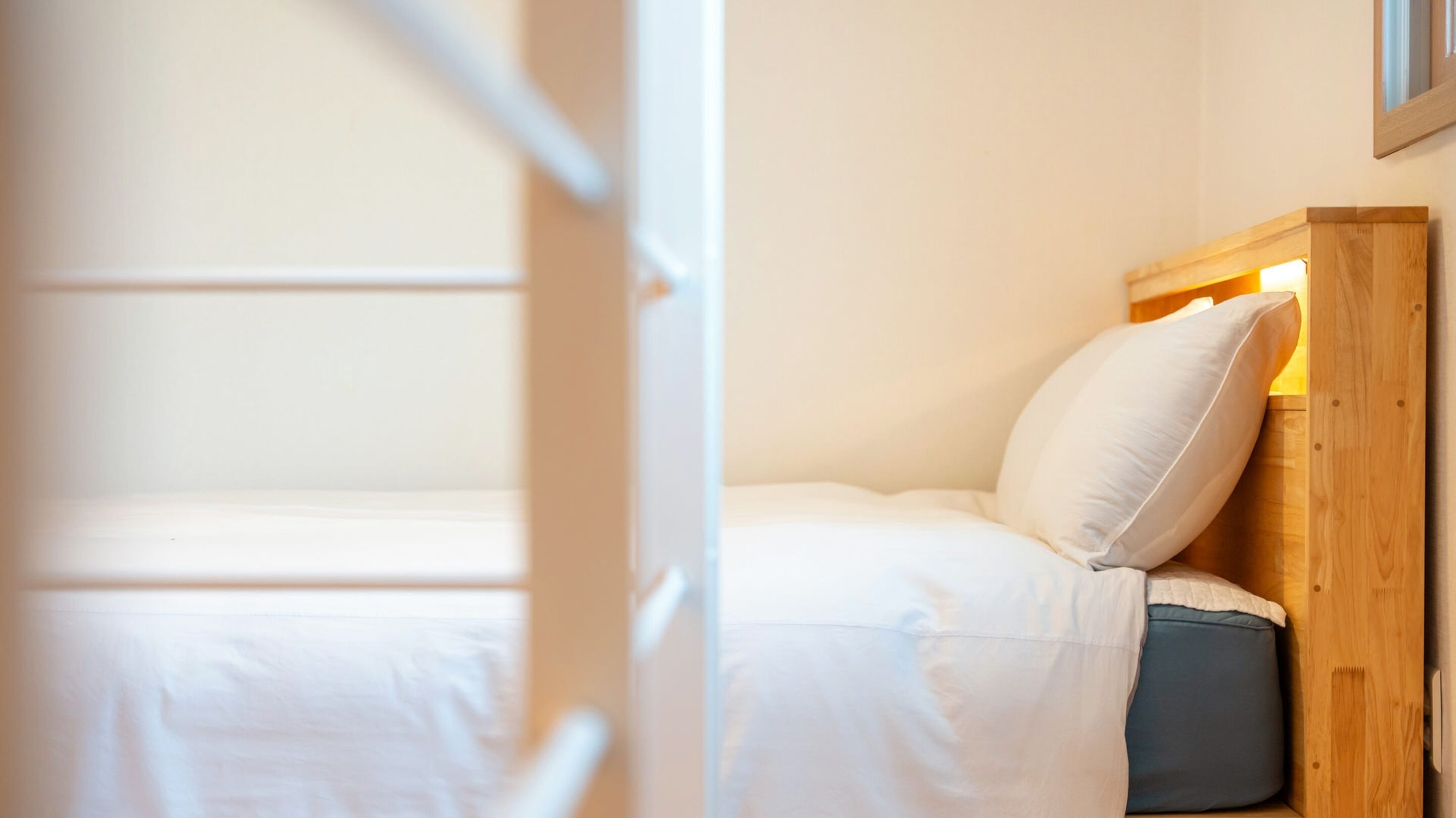 A single bed with white bedding and a wooden headboard.