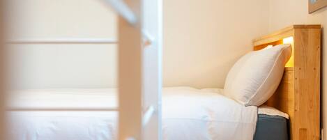 A single bed with white bedding and a wooden headboard.