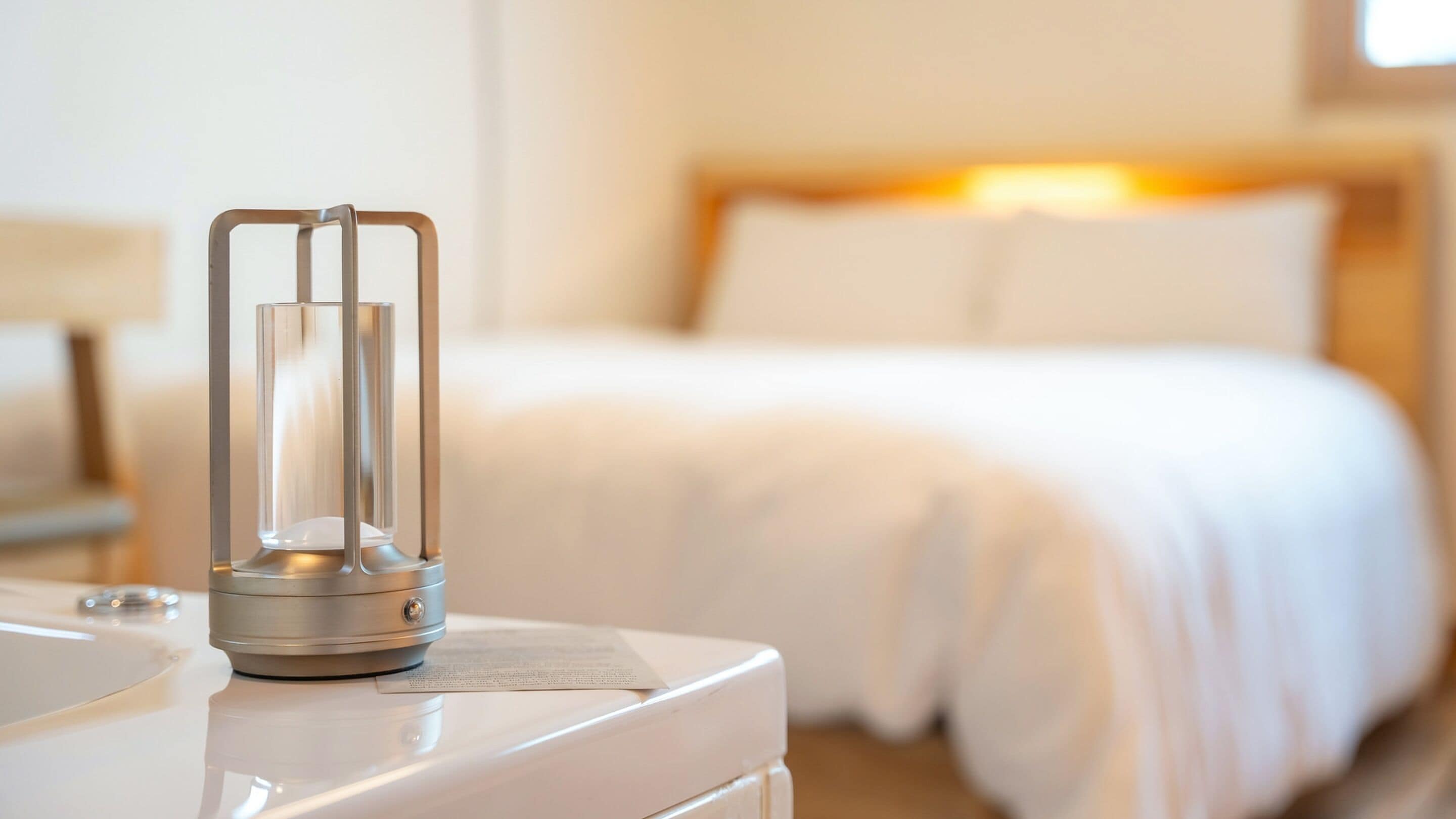 A hotel room with a bed, a bedside table, and a lamp.