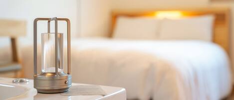 A hotel room with a bed, a bedside table, and a lamp.