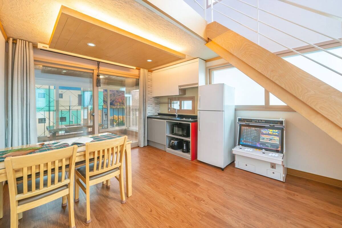 Een moderne keuken met houten vloer, een eethoek met tafel en stoelen, een keukeneiland en een inbouwmagnetron.