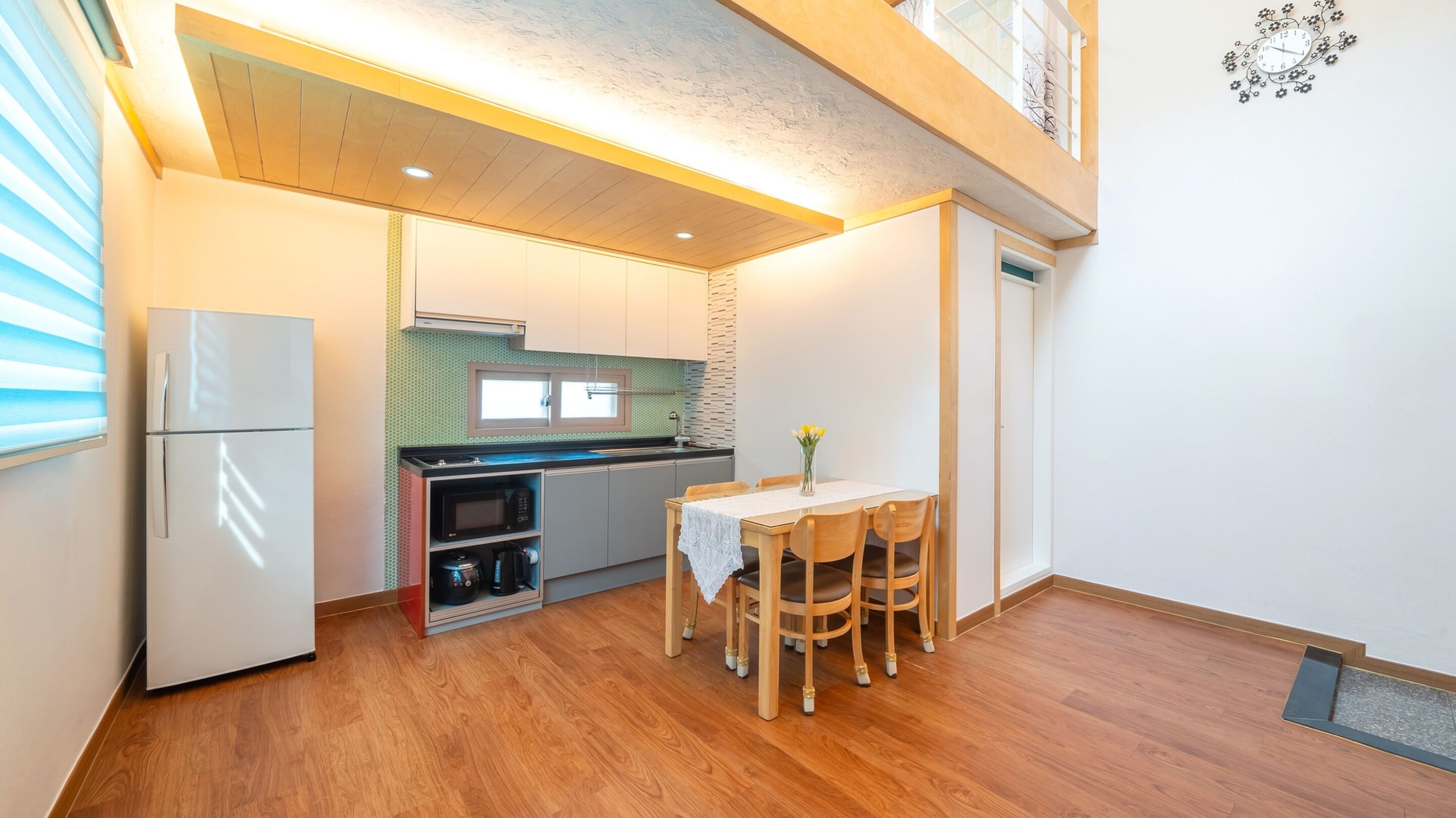 A compact kitchen with a refrigerator, microwave, stove, and dining table with chairs.