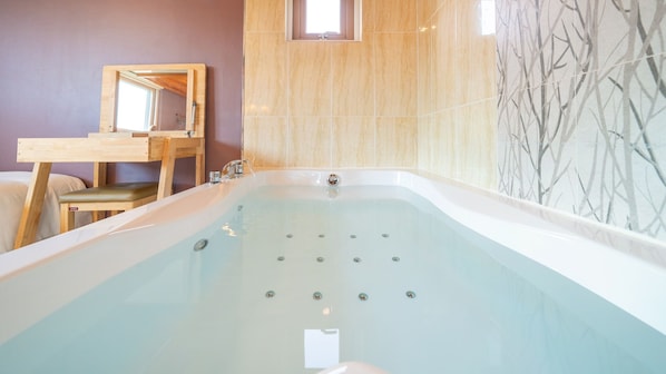 A bathroom with a large bathtub, wooden vanity, and a mirror. - Gapyeong Arom Spa Pension (Gapyeong)