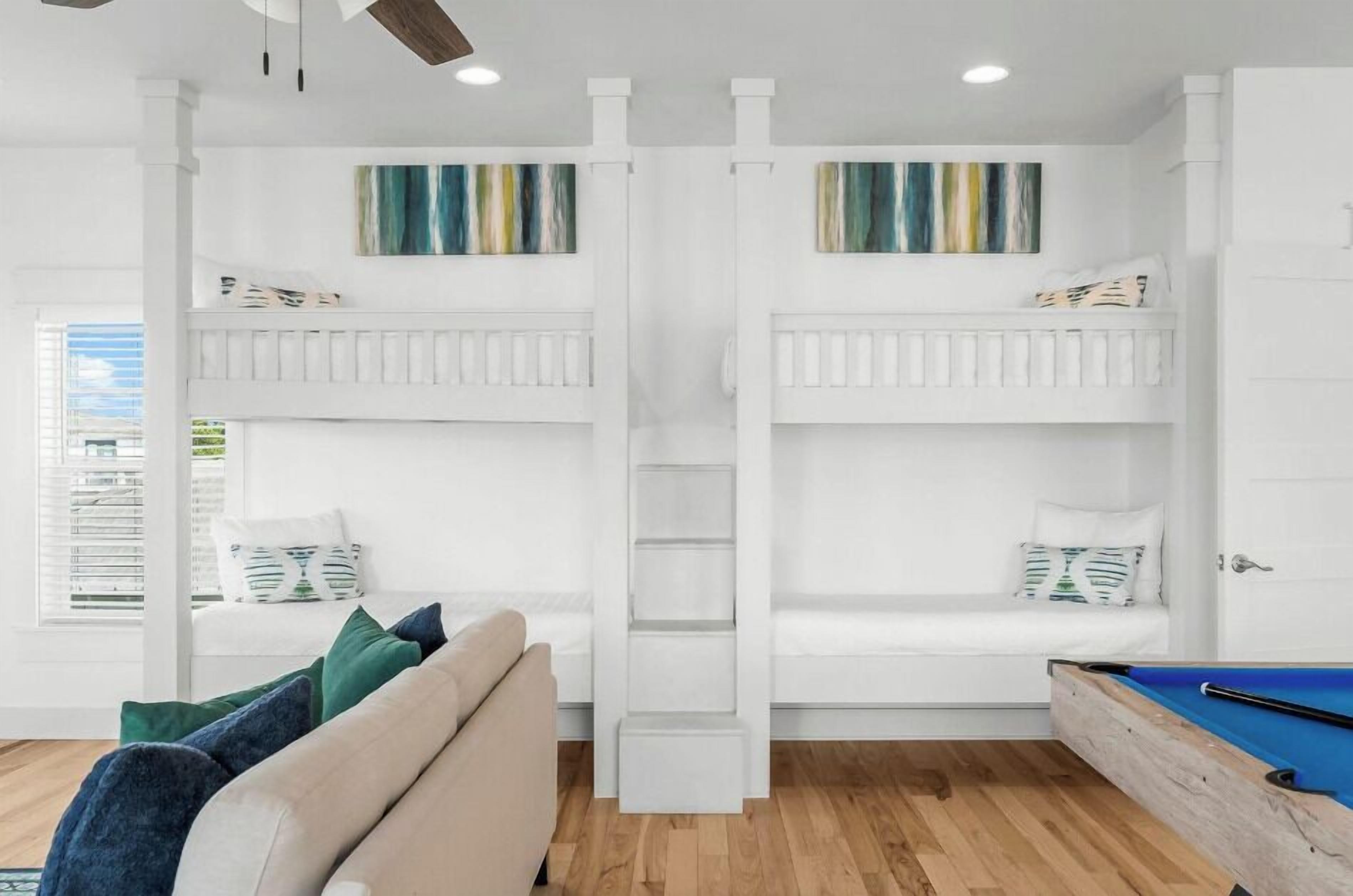 A room with bunk beds, a pool table, and a sofa.