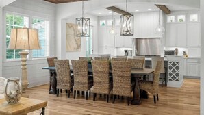 Una cocina moderna con armarios blancos, un comedor con sillas de mimbre y un techo de madera.