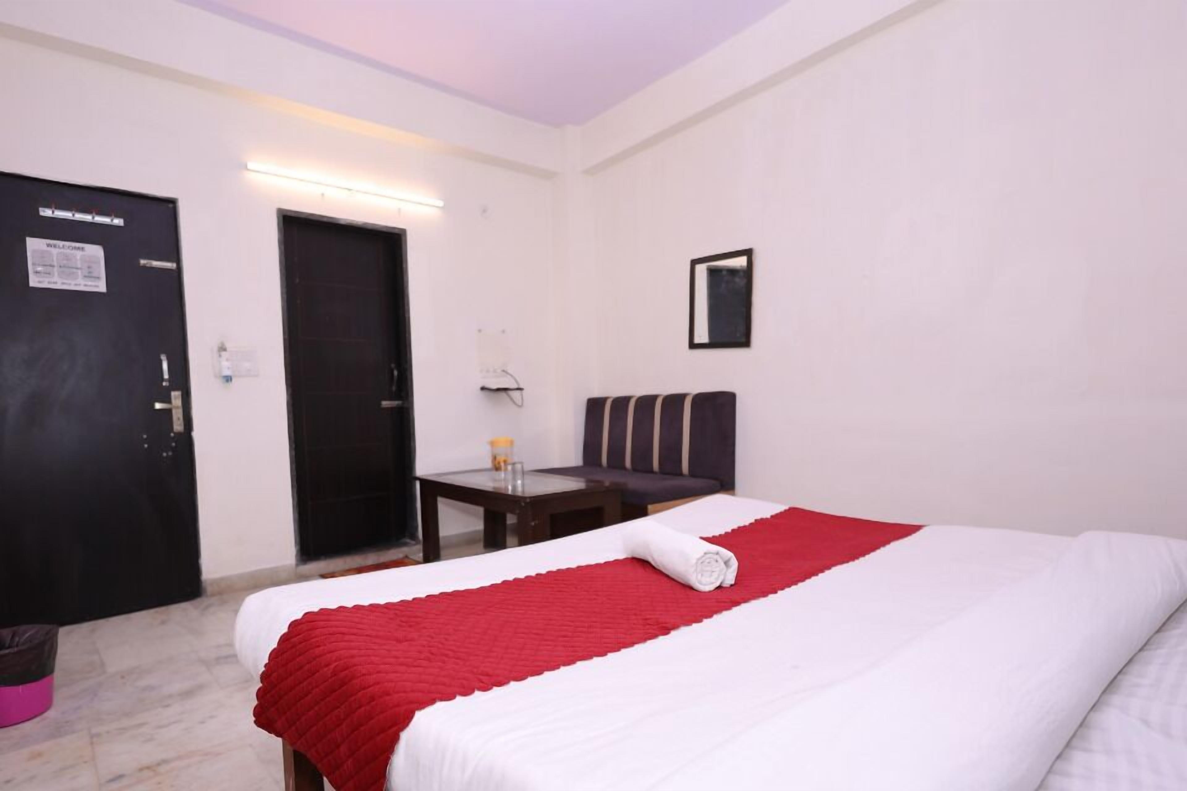 A hotel room with a bed, a desk, a chair, and a door.