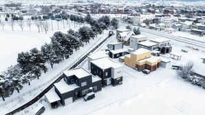 An aerial view of a residential area with modern houses, a snow-covered landscape, and a clear sky. - THE SHELBOURNE FURANO (Furano)