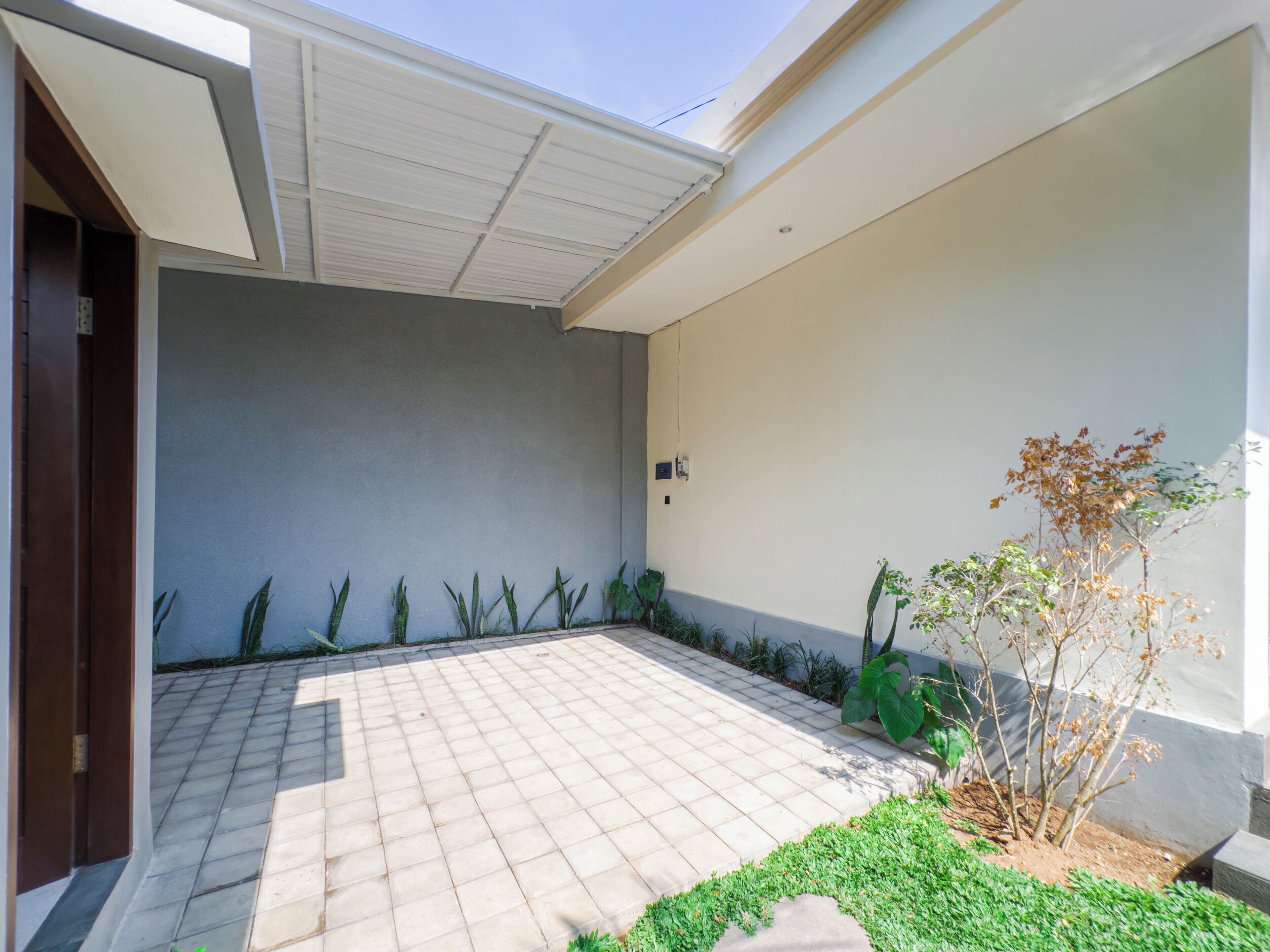 A spacious patio with a tiled floor, surrounded by low walls and a variety of plants.