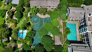 An aerial view of a residential area with multiple swimming pools surrounded by lush greenery and traditional architecture. - Potala Hot Spring Resort  Dali (Dali)