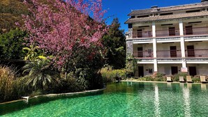 A hotel with a pool, surrounded by lush greenery and flowering trees. - Potala Hot Spring Resort  Dali (Dali)