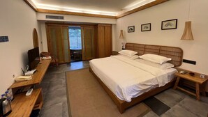 A hotel room with a large bed, wooden headboard, bedside tables, a desk with a chair, and a view through a sliding door to a balcony. - Potala Hot Spring Resort  Dali (Dali)
