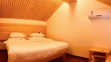 A bedroom with a wooden sloped ceiling, a bed with white bedding, a small bedside table, and a wall-mounted air conditioning unit.