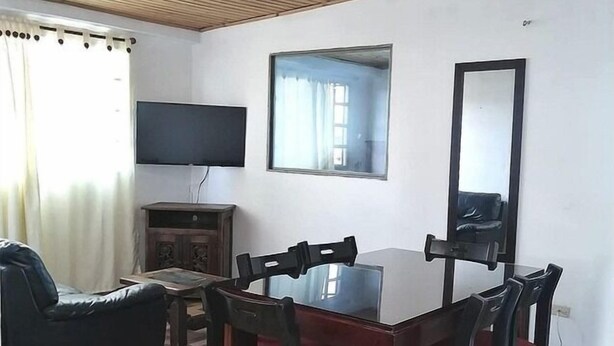 Ein Essbereich mit Holztisch und -stühlen, einem Fernseher an der Wand und einem großen Spiegel.