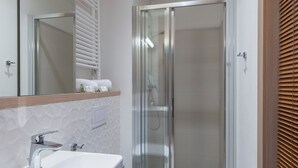 Un bagno moderno con lavandino bianco, specchio e cabina doccia in vetro.