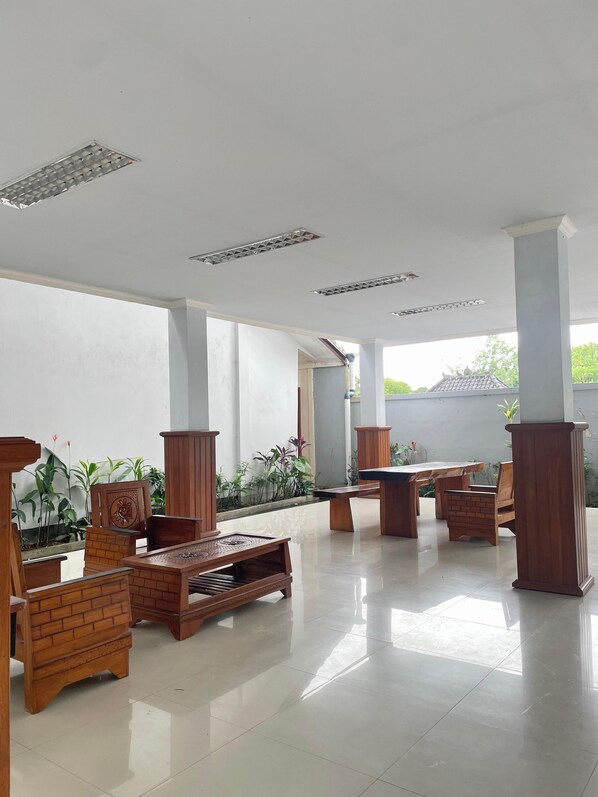 A spacious indoor area with a tiled floor, wooden furniture, and columns. - Giri Kusuma Hotel (Payangan)