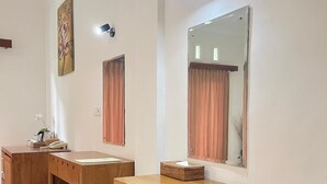 Ein Zimmer mit zwei Holztischen, einem großen Spiegel und einer Wandleuchte.
