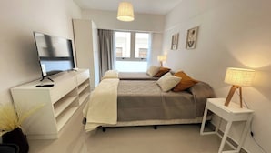 Une chambre d’hôtel moderne équipée d’un lit, d’une télévision, d’un bureau et d’une lampe.