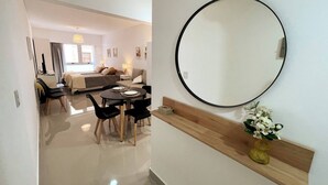 Une chambre d’hôtel moderne avec un coin repas, un grand miroir et un vase rempli de fleurs.