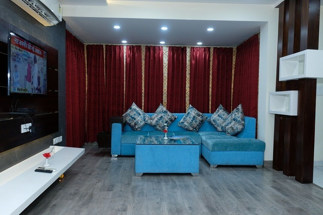 A modern living room with a blue sofa set, a coffee table, and a flat-screen TV mounted on the wall.