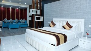 Een moderne slaapkamer met een groot bed, een blauwe zithoek en een decoratief wandpaneel.
