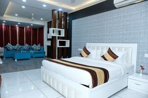 Un dormitorio moderno con una cama grande, un conjunto de sofá azul y un panel decorativo en la pared.