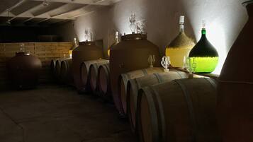 Un sótano con barriles de madera y grandes recipientes de cerámica, presumiblemente para añejar vino.