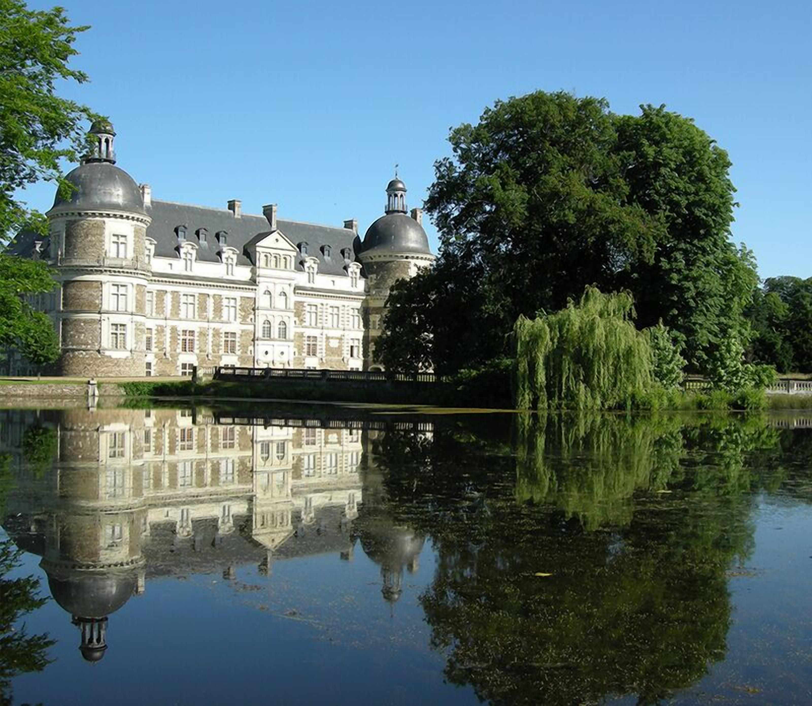 A large, historic building with multiple domes and a reflection in the water.