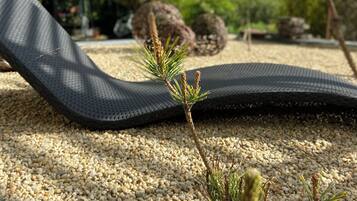 Un tapis noir sur une surface de gravier, avec une petite plante au premier plan.