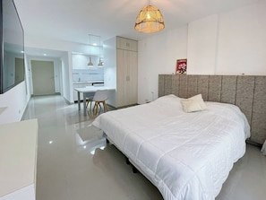 A modern hotel room with a large bed, a dining area, and a kitchenette. - Modern & Cozy Studio in San Telmo With Pool and Balcony (Buenos Aires)