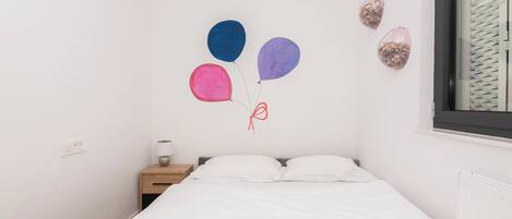 A bedroom with a bed, a nightstand, and wall decorations including balloons and a wall clock.