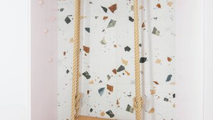 A room with a wooden floor, a white wall with a terrazzo pattern, and a wooden swing suspended from the ceiling. - Bellavista Apartment Koper (Koper)