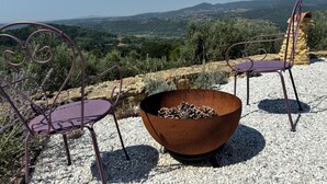 Two purple metal chairs and a rust-colored bowl on a gravel surface with a scenic view of hills and trees in the background. - Villa Tramontalba - luxury villa, infinity pool, perfect for exploring Tuscany (Toscana)