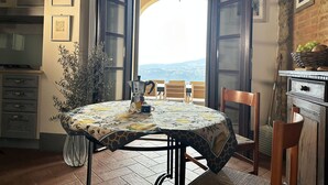 A dining area with a round table, chairs, and a view of the countryside through an open door. - Villa Tramontalba - luxury villa, infinity pool, perfect for exploring Tuscany (Toscana)