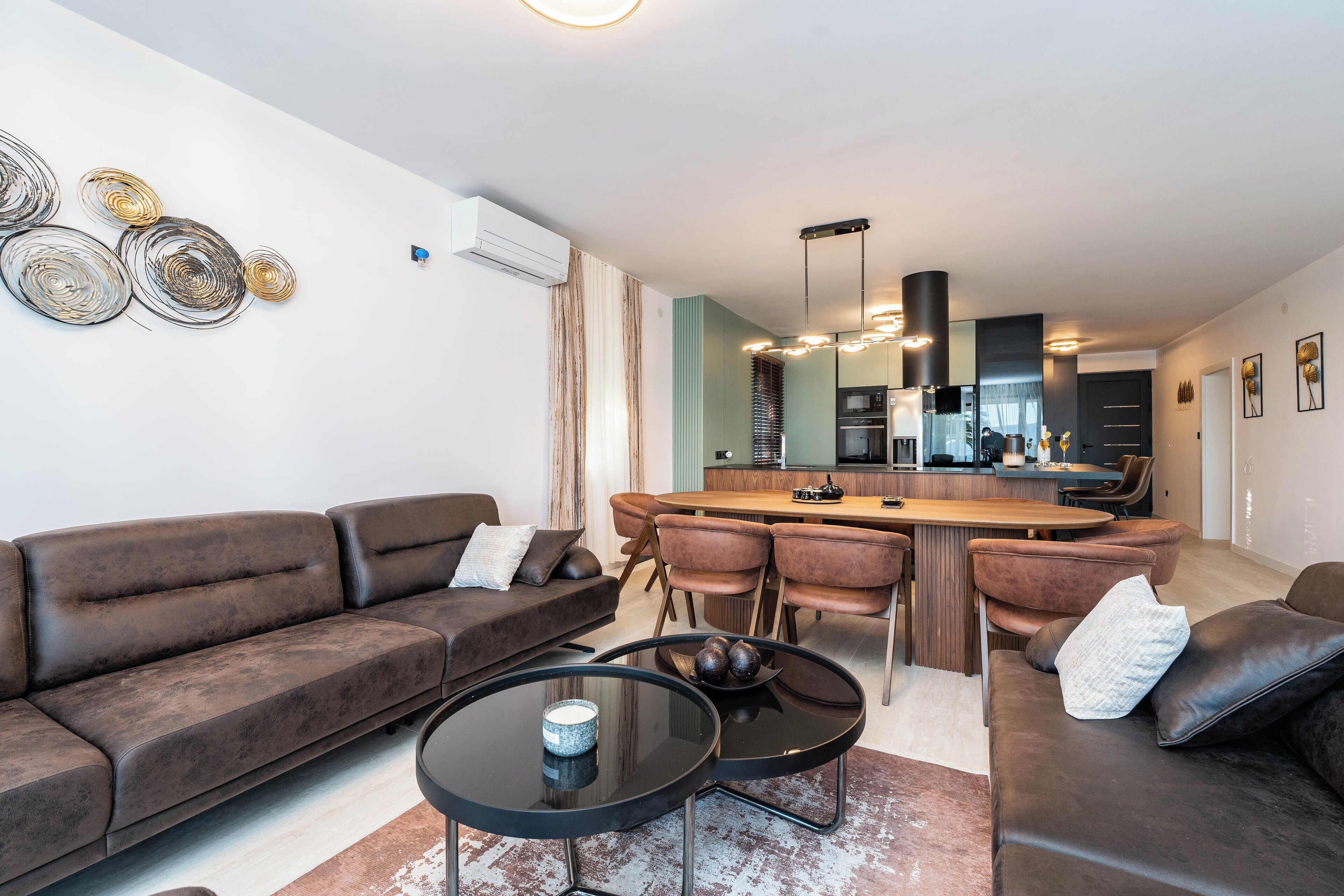 A modern living room with a sofa, coffee table, and dining area with chairs.