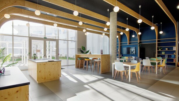 Un interior moderno con detalles de madera, ventanas amplias y una variedad de opciones de asiento.