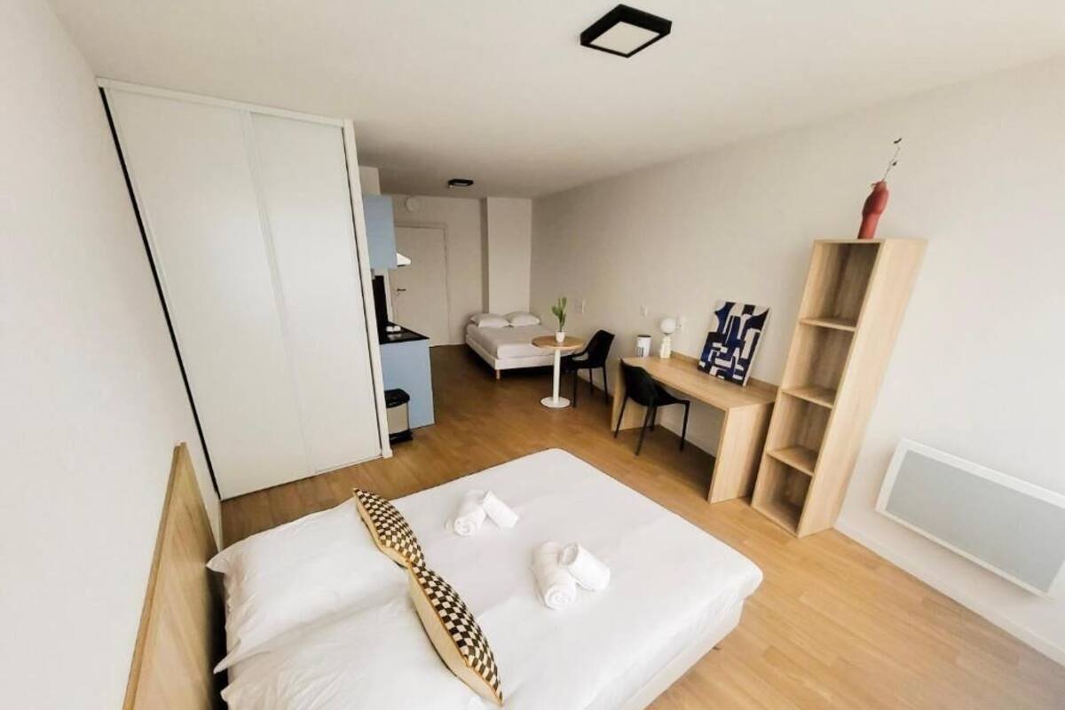 Una habitación de hotel moderna con una cama, un escritorio, una silla, un armario y un pequeño rincón de estar con una mesa y sillas.