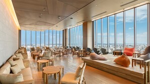 Un salón amplio con techos altos, ventanas grandes y vistas a la ciudad.
