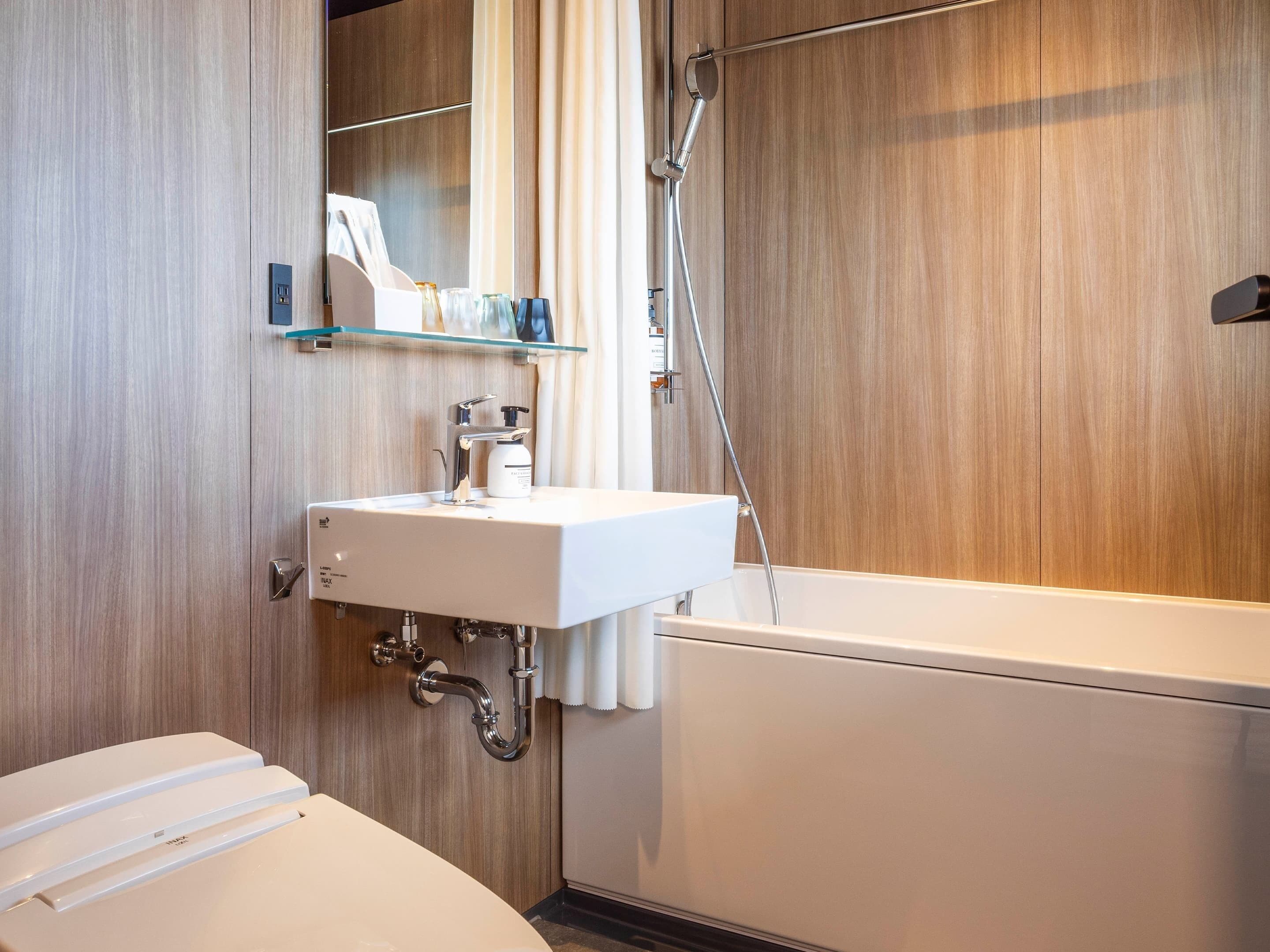 A modern bathroom with a white sink, a glass shelf above it, and a bathtub.