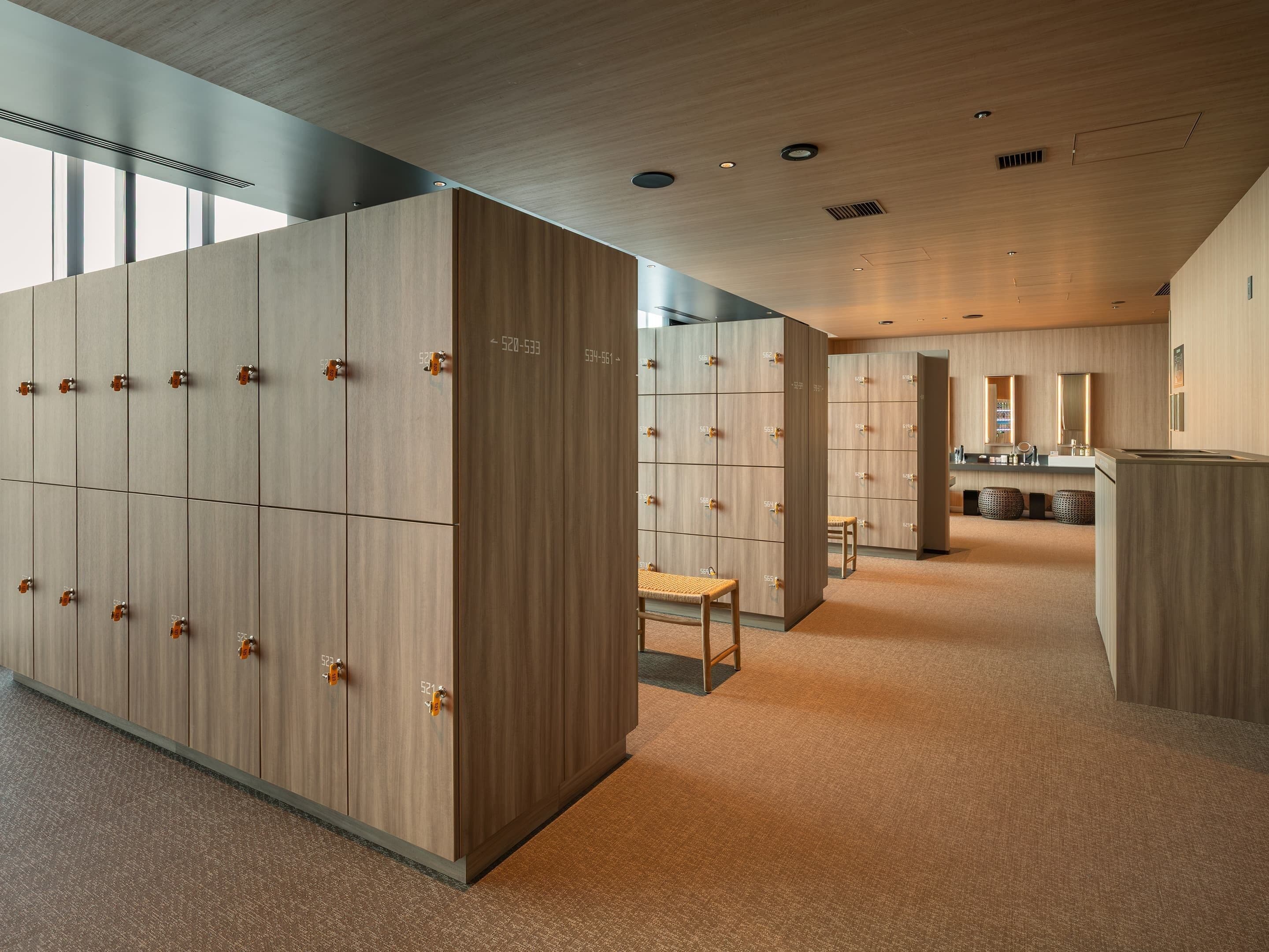 A modern hotel lobby with lockers, a reception desk, and a mirror.