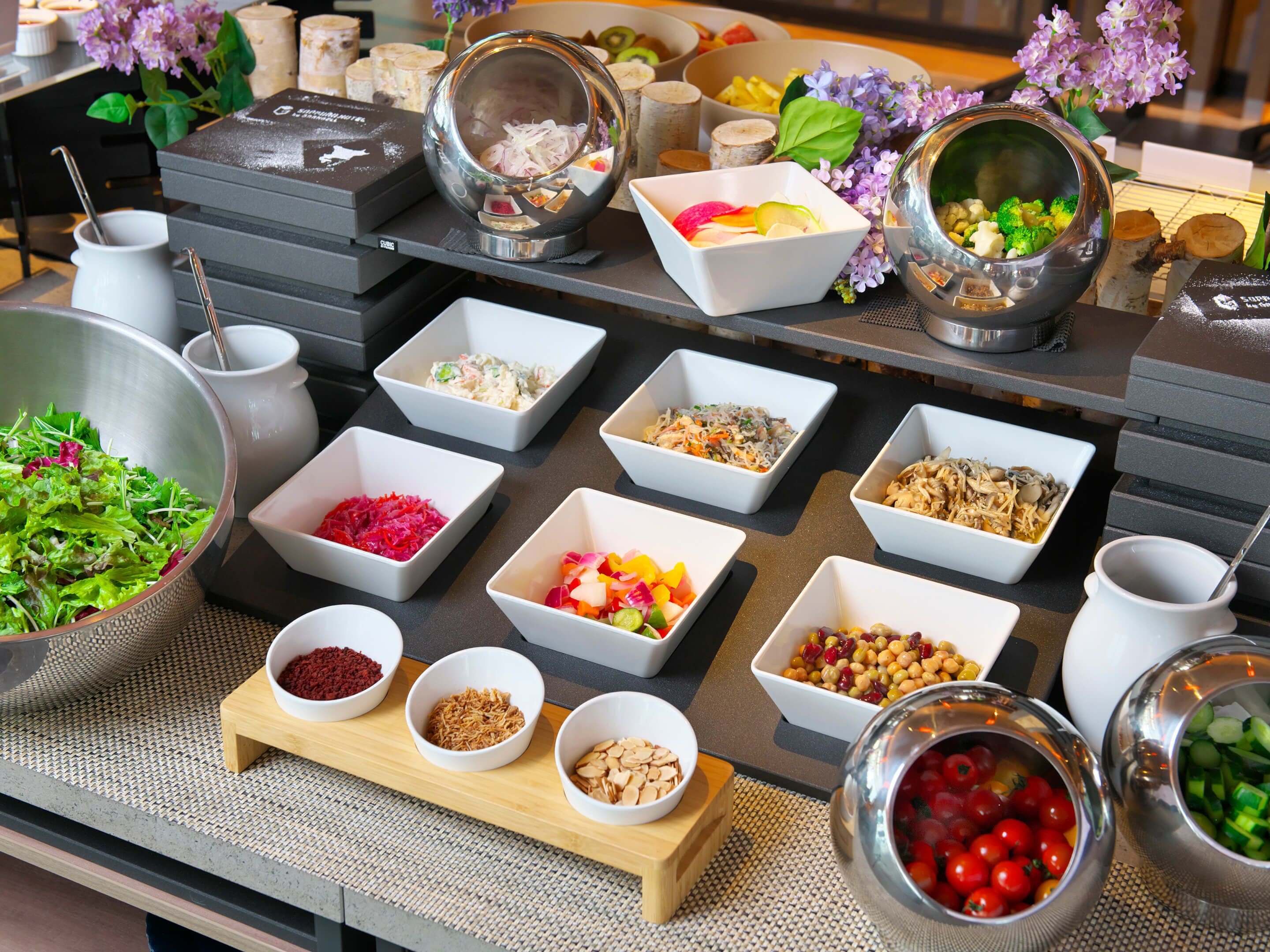 A buffet table with various food items and bowls.